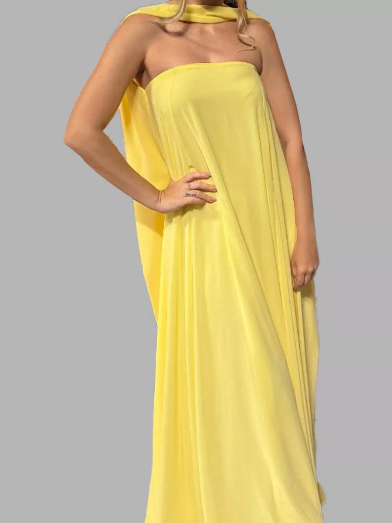 Back view of butter yellow draped halter maxi dress showing open back and floor-length flowing silhouette