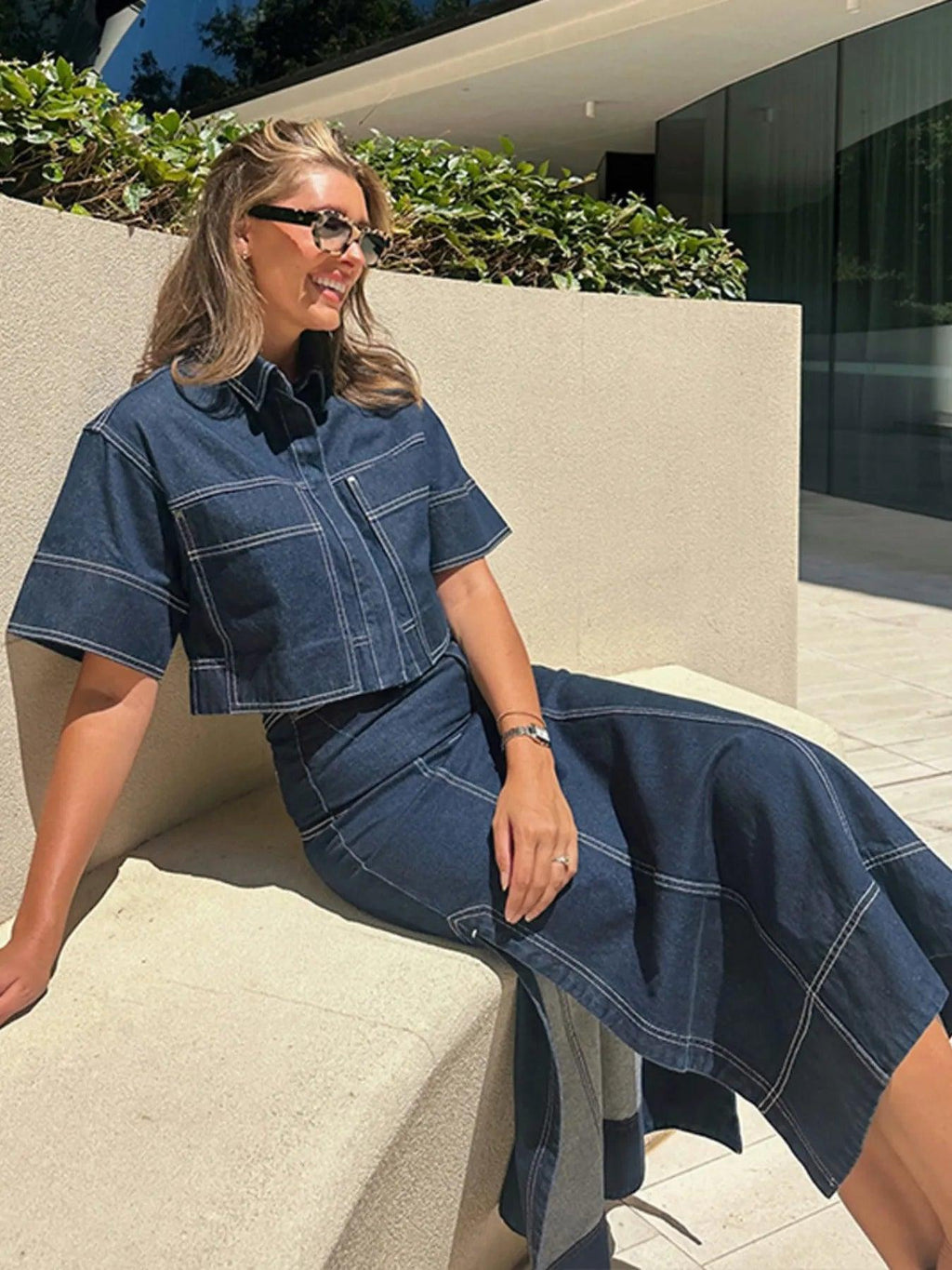 Midnight blue contrast-stitch denim top, sleeve and pocket detail close-up.