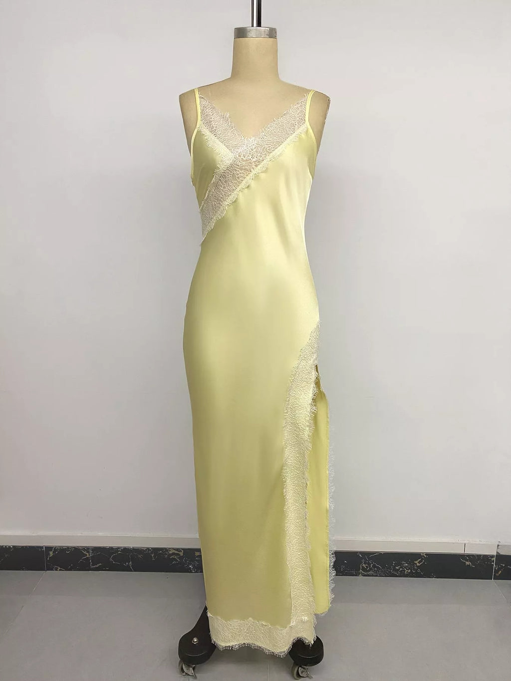 Studio front view of the Pastel Yellow Lace-Trim Slip Midi Dress on a mannequin, showing the V-neck eyelash lace, asymmetric lace panel across the waist, and lace-trimmed hem.