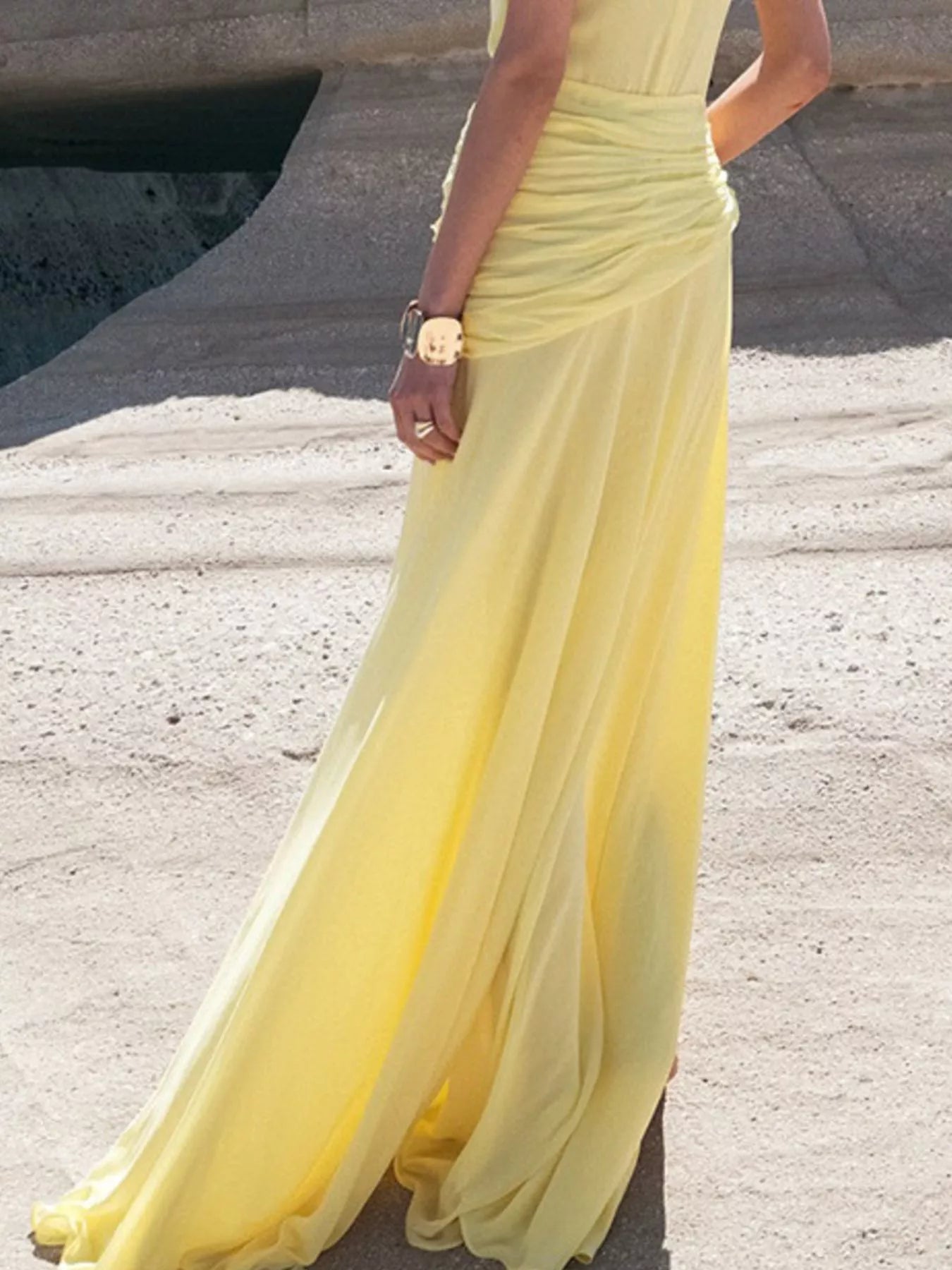 Pastel Yellow Sleeveless Ruched Maxi Dress photographed in motion, lower-body view showing the lightweight skirt billowing through the high side slit.