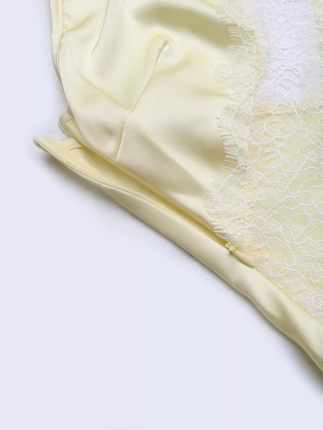 Close-up of the lace-trimmed edge of the Pastel Yellow Lace-Trim Slip Midi Dress, showing the eyelash lace finish against the satin fabric.