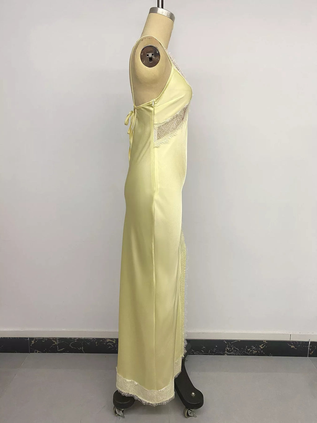Side profile of the Pastel Yellow Lace-Trim Slip Midi Dress on a mannequin, showing the high side slit and the eyelash lace trim running from the slit to the hem.