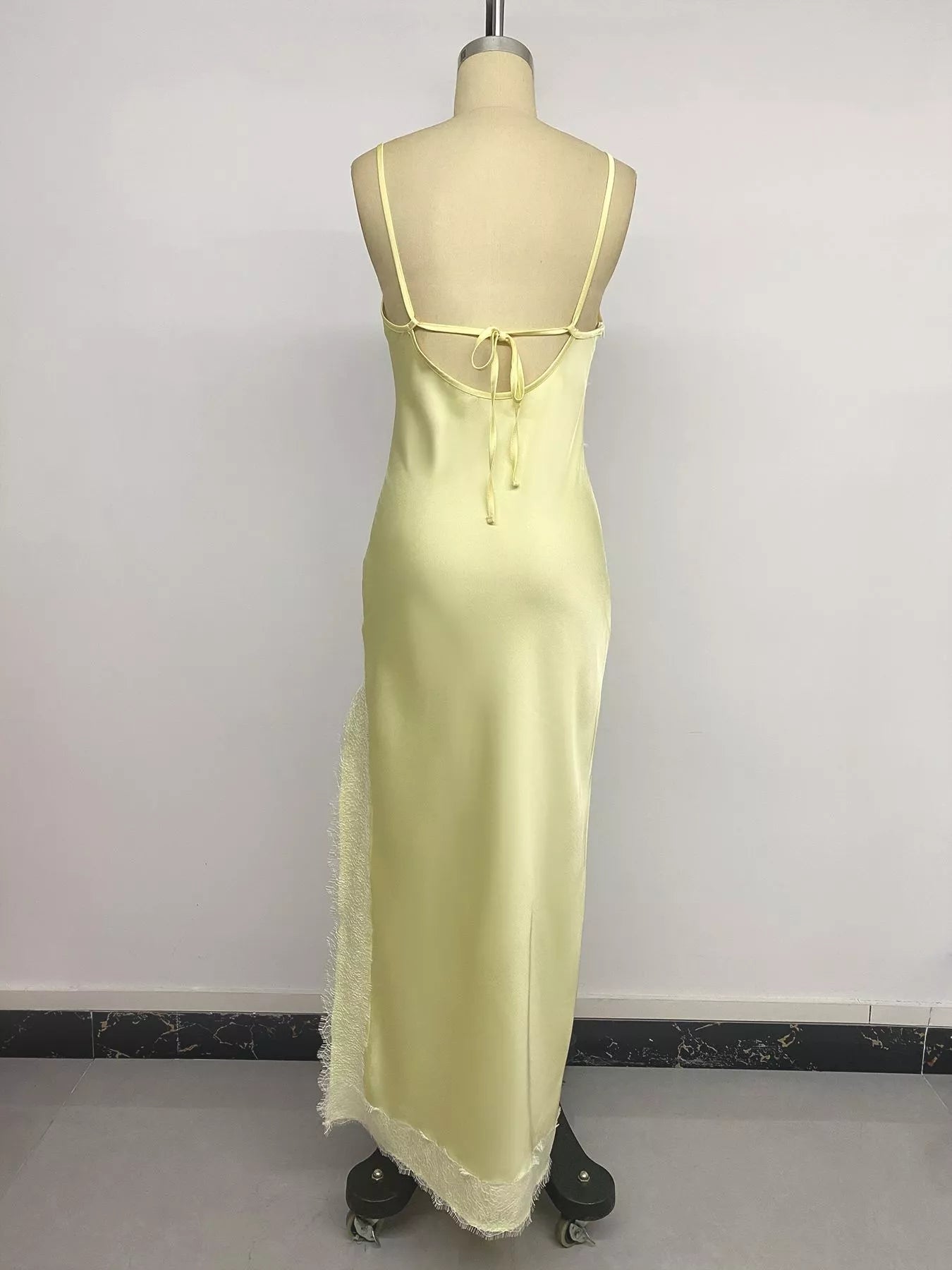 Studio back view of the Pastel Yellow Lace-Trim Slip Midi Dress on a mannequin, showing the low scoop back with adjustable tie-strap closure and the lace-trimmed hem.